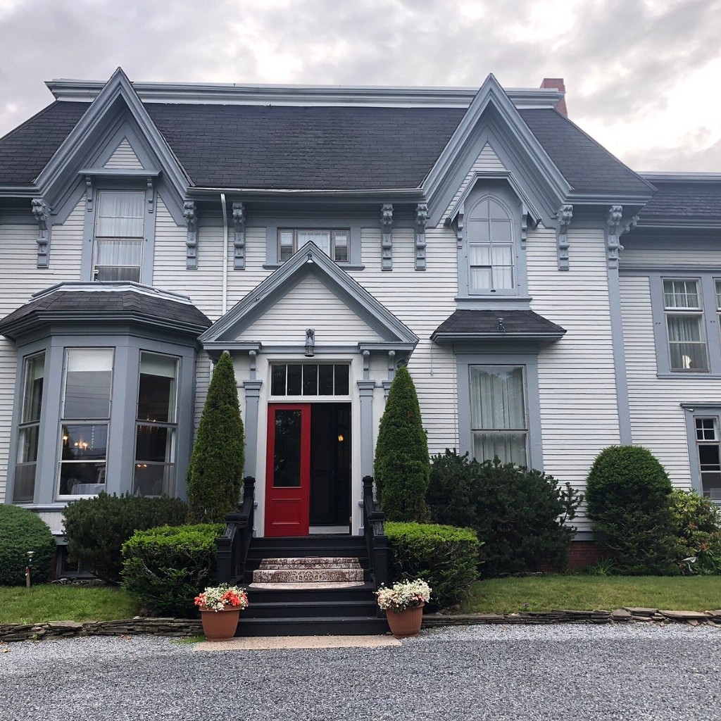 The front of the Shadow Lawn Inn, a white house with a red door